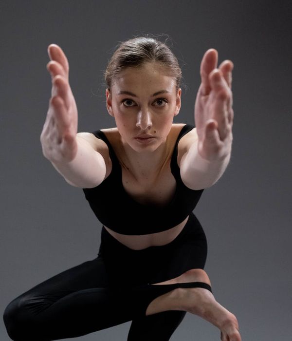 A young woman practicing a graceful yoga balance pose in a dark studio.